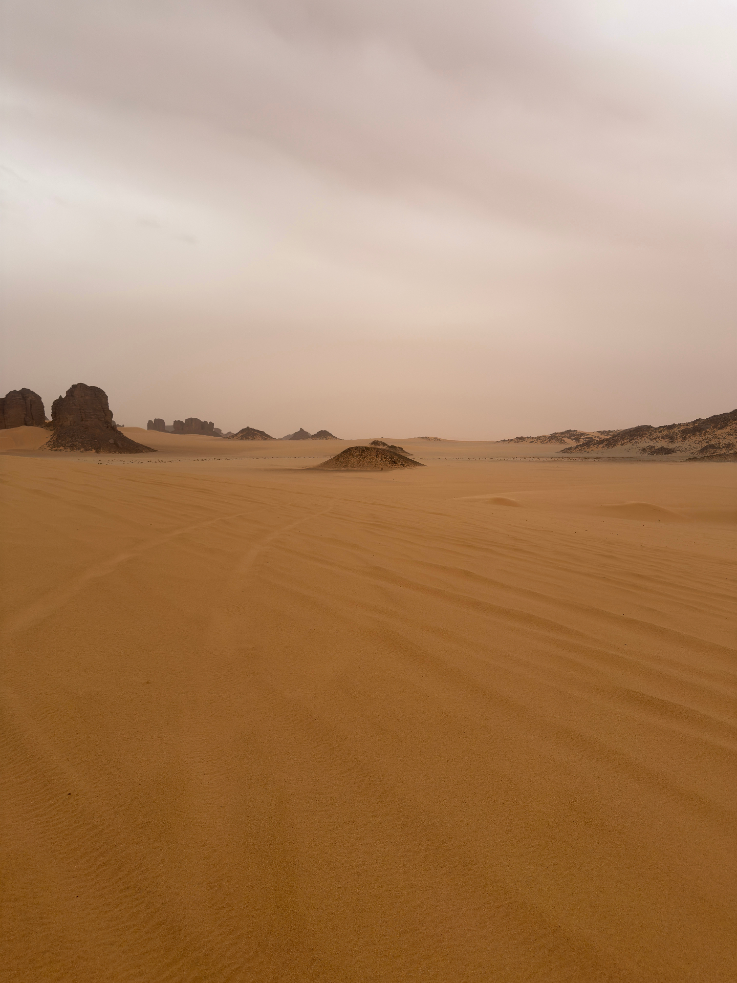 Plaine de sable orangé, aiguilles de roche à l’horizon