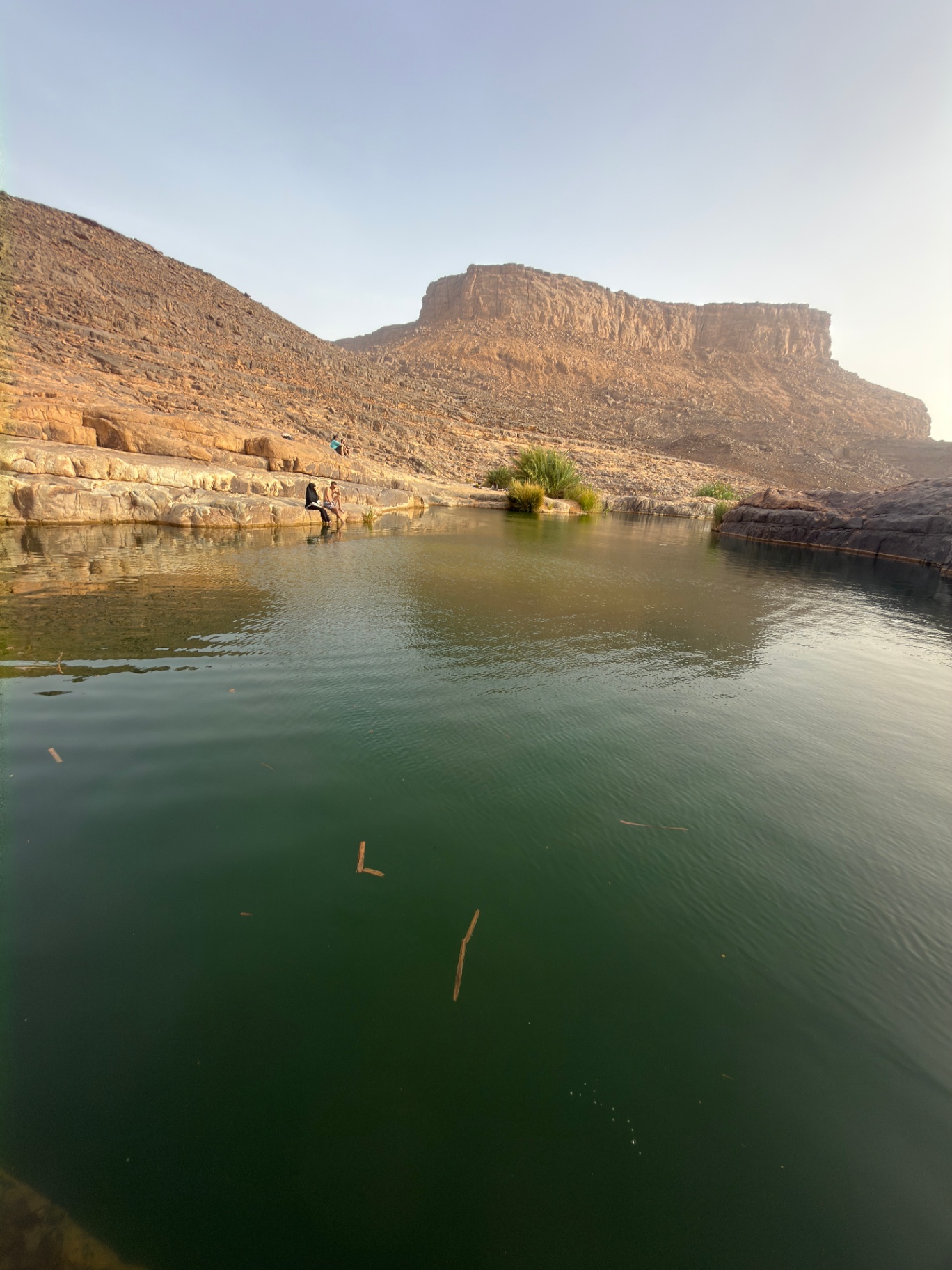 Reflet vert d’une guelta au pied d’une mesa de grès