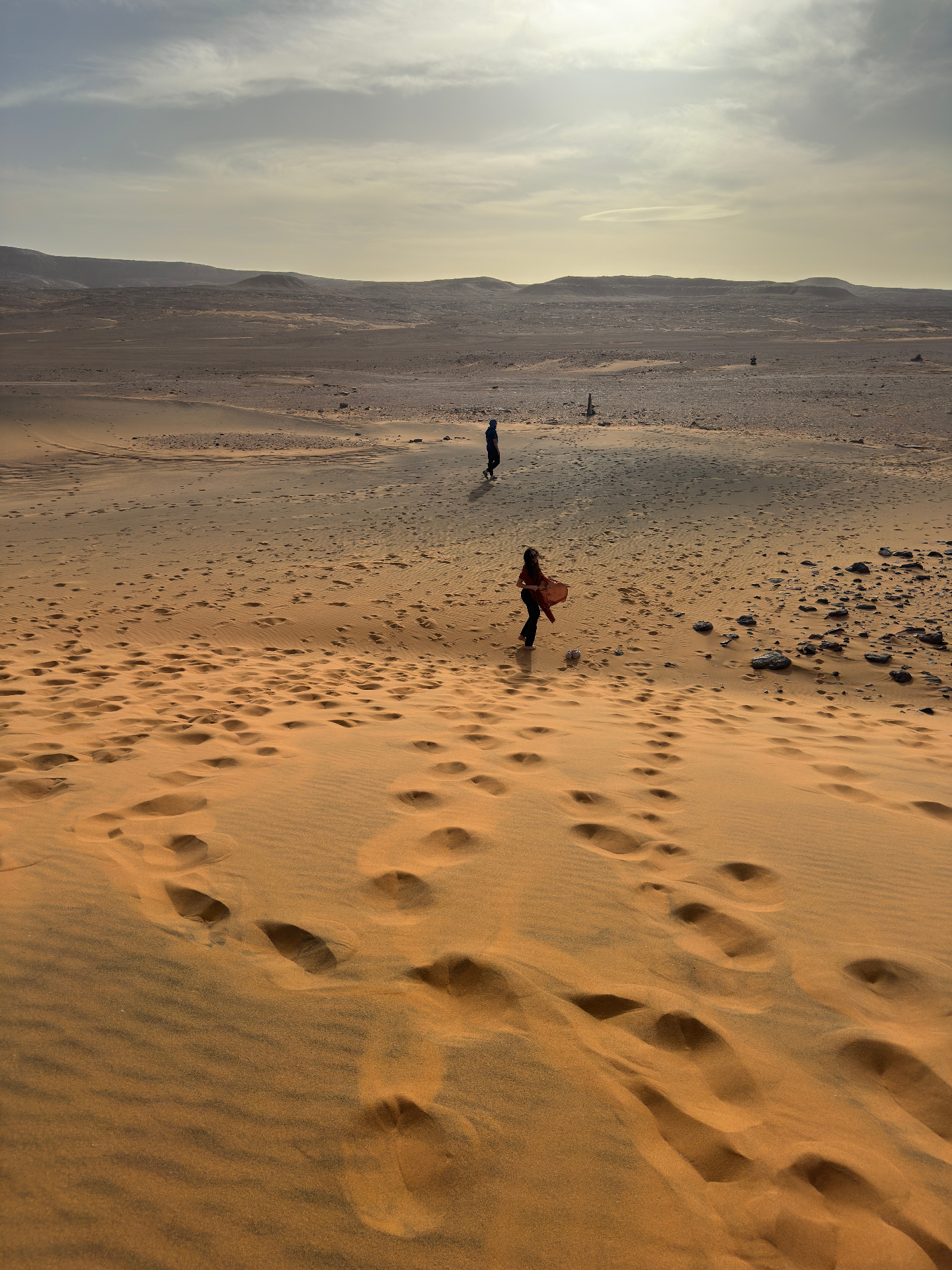 Voyageurs marchant sur les dunes au soleil couchant