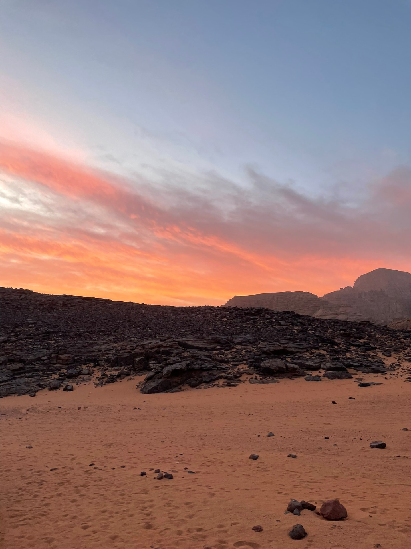 Ciel du désert embrasé au crépuscule sur les reliefs de la Tadrart